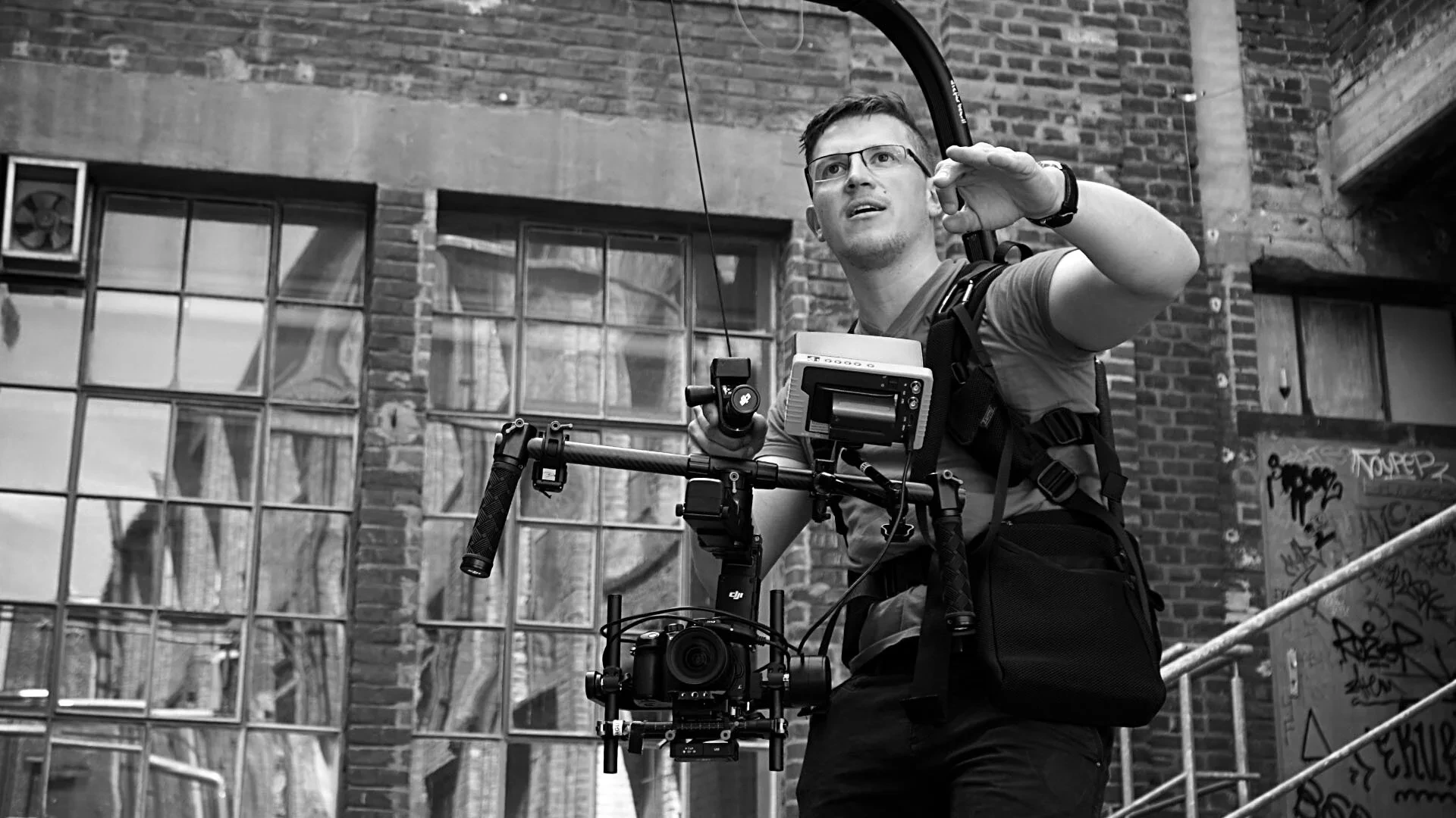 Christian Schmitz in Aktion mit Gimbal-Rig vor urbaner Kulisse, Schwarz-Weiß