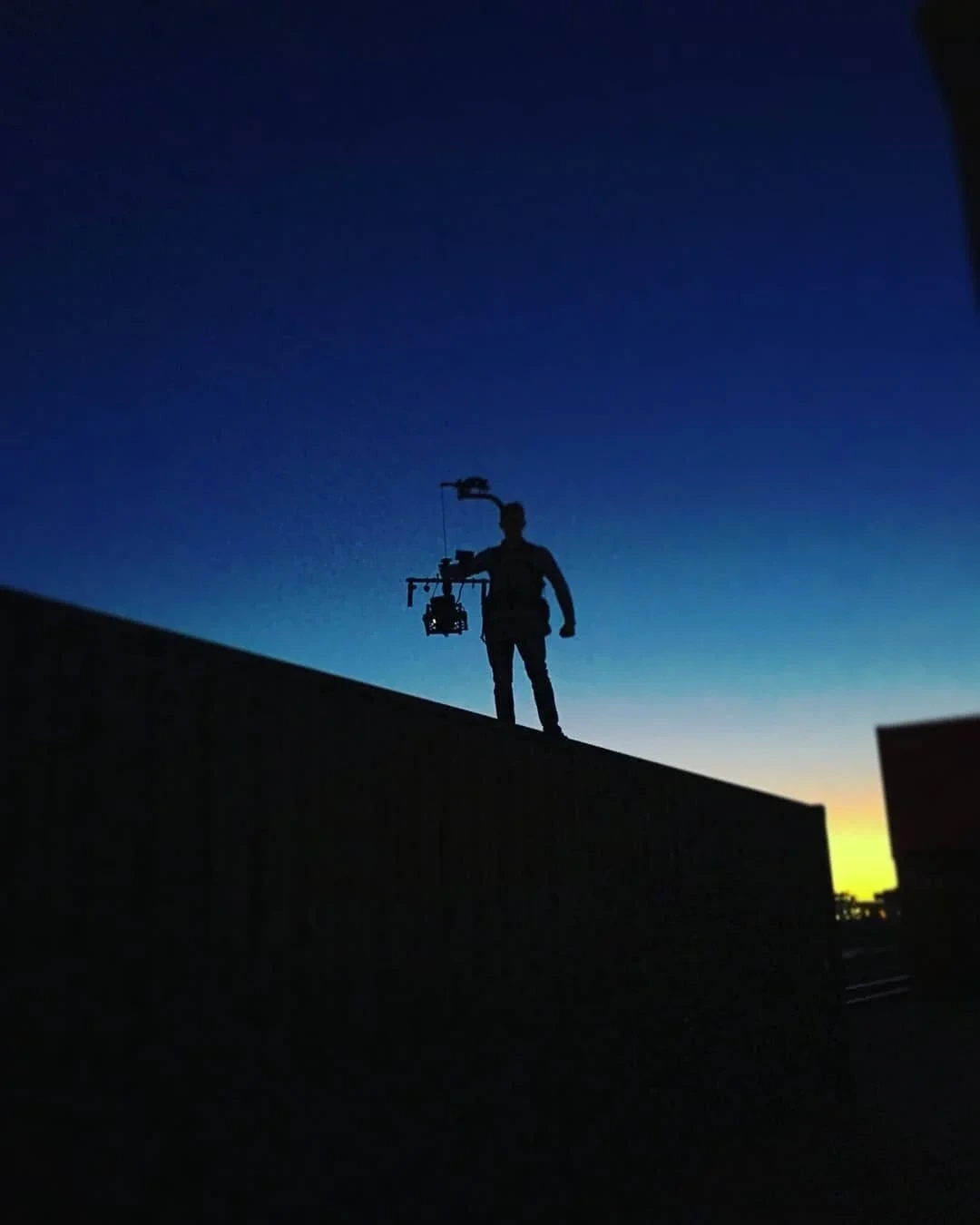 Silhouette Kameramann mit Gimbal gegen dramatischen Sonnenuntergang
